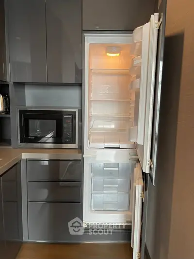 Modern kitchen with sleek cabinetry and built-in fridge and microwave, showcasing contemporary design.