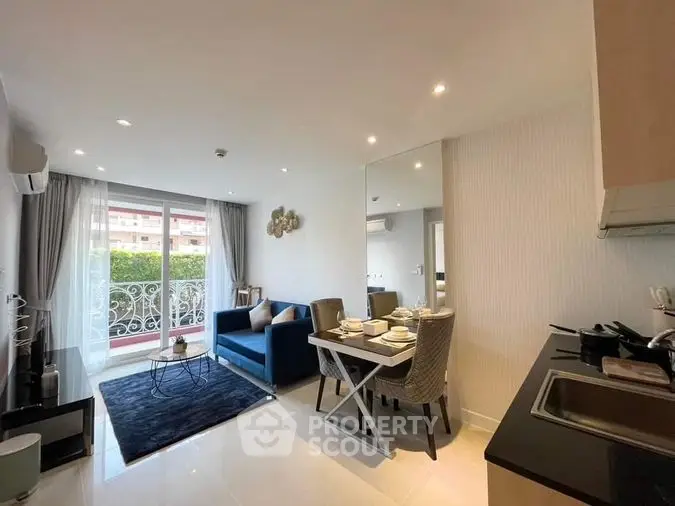 Modern open-plan living space with sleek kitchen, cozy dining area, and comfortable lounge leading to a sunlit balcony, perfect for urban living.