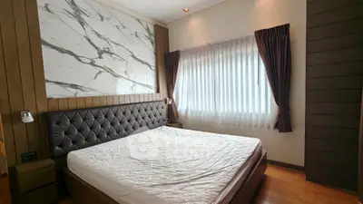Luxurious bedroom with elegant marble accent wall and plush headboard, featuring natural light through large window.