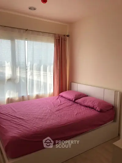 Cozy bedroom with pink bedding and large window offering natural light.