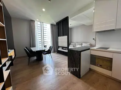 Modern open-plan living room with dining area and sleek kitchen in a stylish apartment.