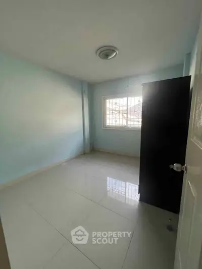 Spacious empty room with tiled floor and natural light, perfect for customization.