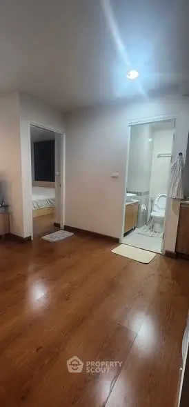 Modern apartment interior with wooden flooring, bedroom and bathroom access.