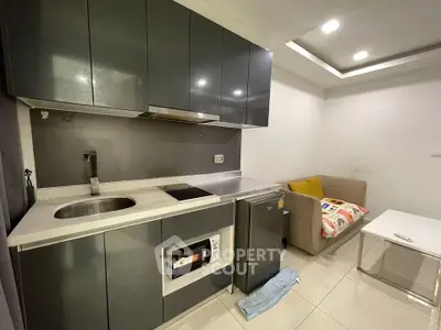 Modern compact kitchen with sleek cabinetry and cozy living area in a stylish apartment.