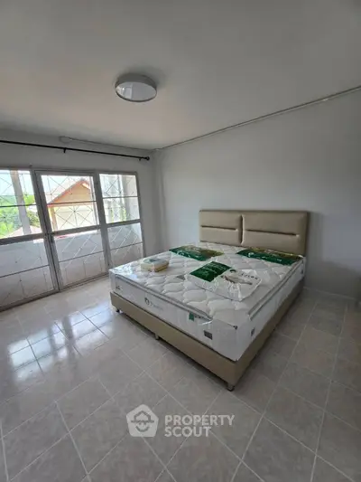 Spacious bedroom with large windows and natural light, featuring a new bed and tiled flooring.