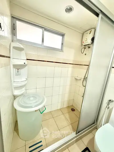 Compact bathroom with shower and water heater, featuring tiled walls and floor.