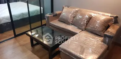 Modern living room with stylish sofa and glass coffee table, adjacent to a cozy bedroom.