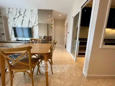 Modern open-plan living and dining area with stylish wooden furniture and marble accents.