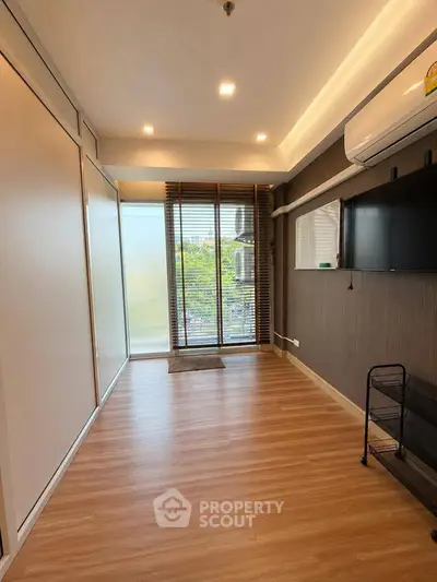 Modern living room with wooden flooring and large windows in a stylish apartment.
