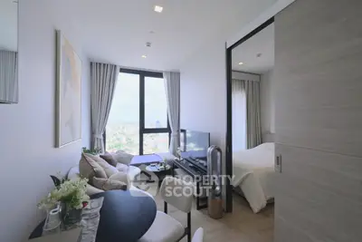 Modern apartment with open living room and bedroom, featuring large windows and stylish decor.