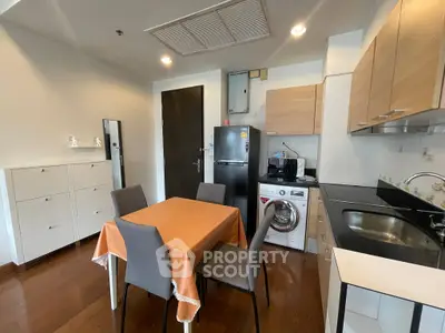 Modern kitchen with dining area, featuring wooden cabinets and integrated appliances.