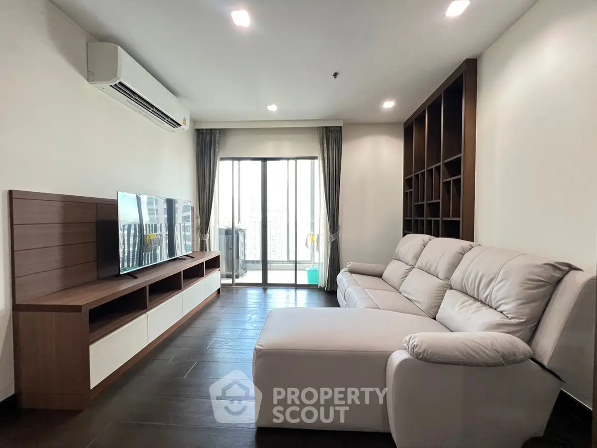 Modern living room with sleek furniture and city view balcony.