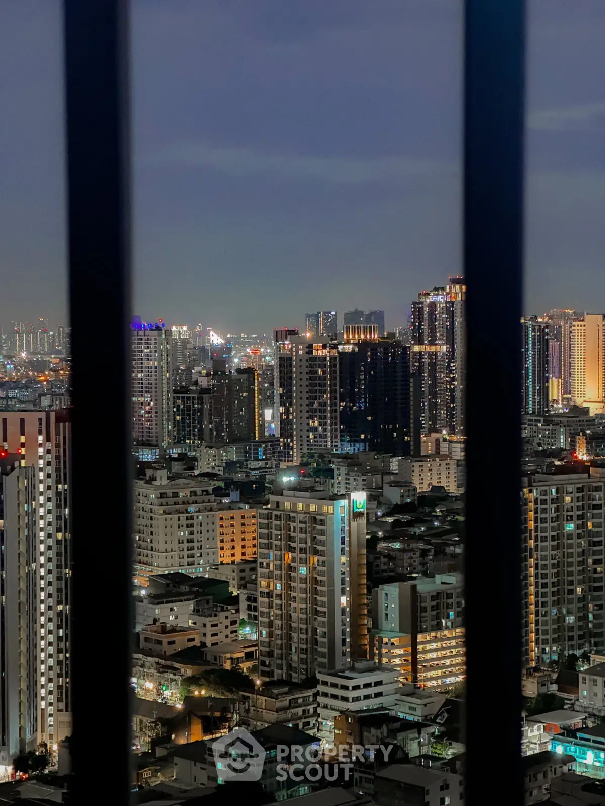 Stunning cityscape view of illuminated high-rise buildings at night, showcasing urban living and vibrant skyline.