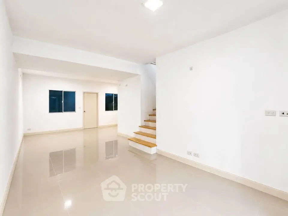 Spacious modern living room with sleek staircase and glossy tiled floors
