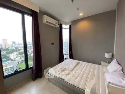 Modern bedroom with large windows offering stunning city views in a high-rise apartment.