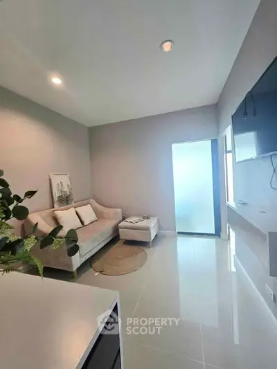 Modern living room with sleek design, cozy sofa, and wall-mounted TV in a bright apartment.