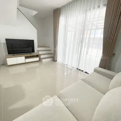 Spacious modern living room with large windows and elegant staircase