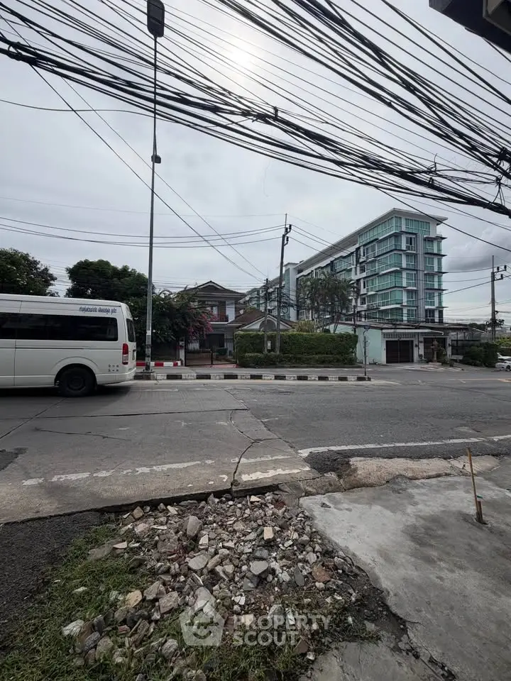 Urban street view with modern building and parked vehicles, showcasing city living environment.