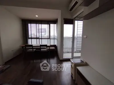 Modern living room with balcony access and stylish dining area, featuring large windows for natural light.