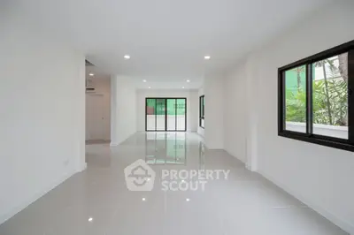 Spacious modern living room with large windows and glossy tiled floors