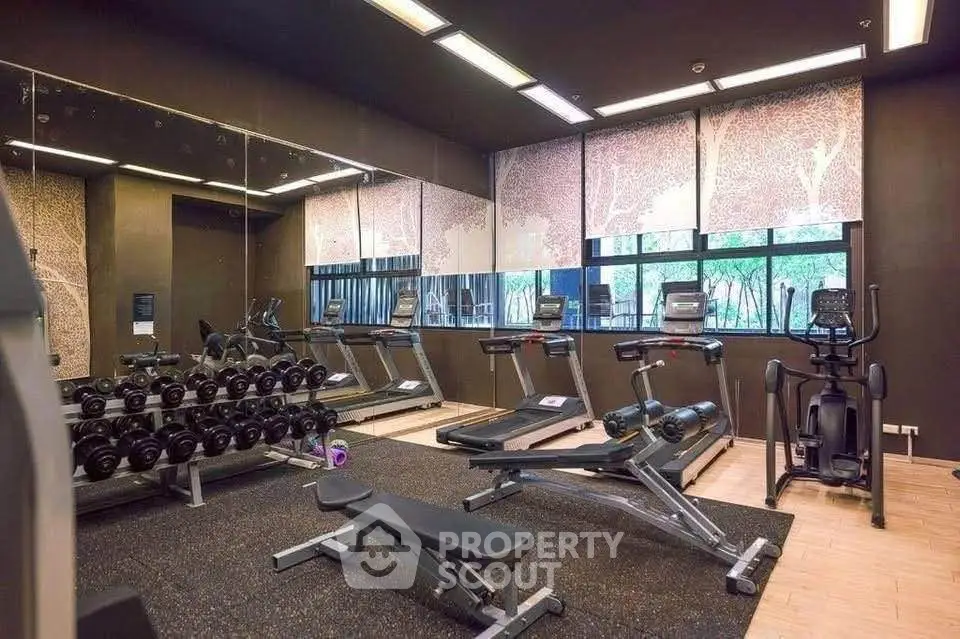 Modern gym with state-of-the-art equipment and mirrored walls in luxury residential building.