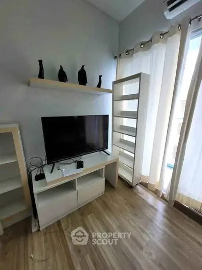 Modern living room with TV, wooden flooring, and stylish decor