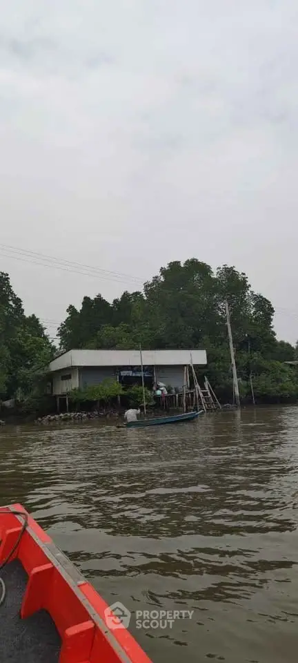 Riverside property with lush greenery and a small boat docked nearby.