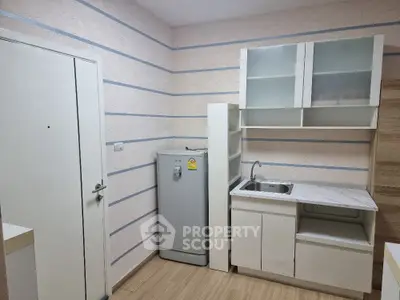 Compact kitchen with modern cabinetry and sleek refrigerator in a cozy apartment.