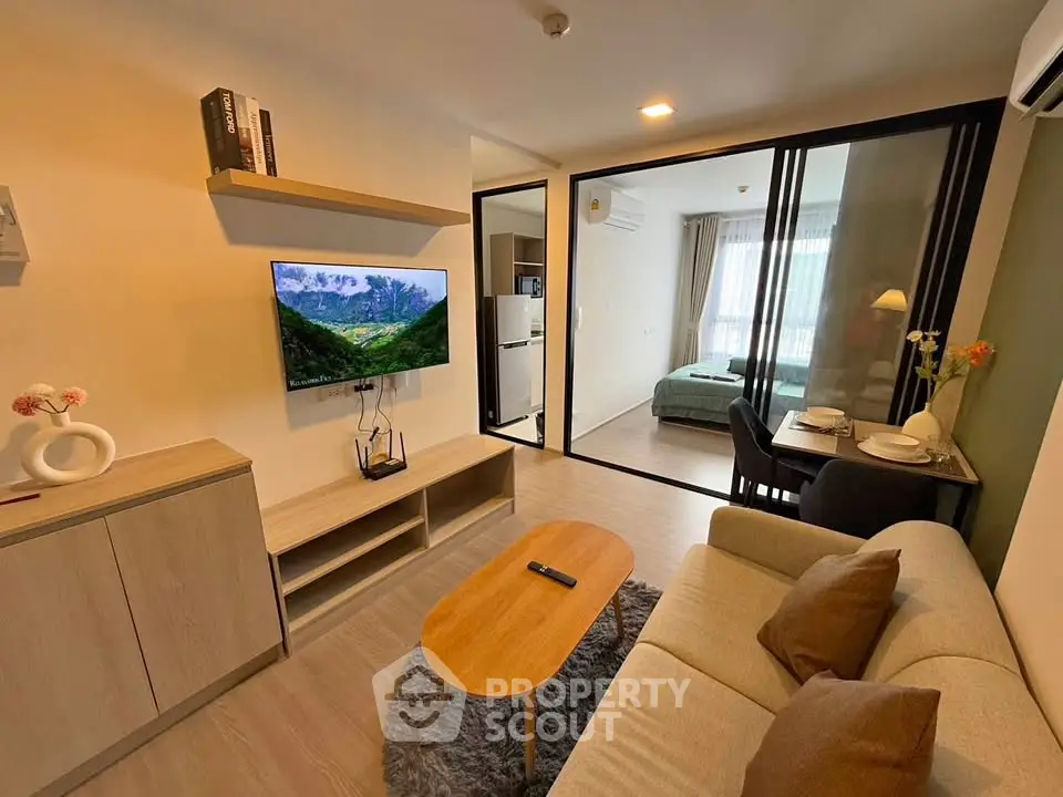 Modern living room with open layout and stylish decor, featuring a cozy sofa and wall-mounted TV.