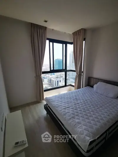 Modern bedroom with large windows offering stunning city views in a high-rise apartment.