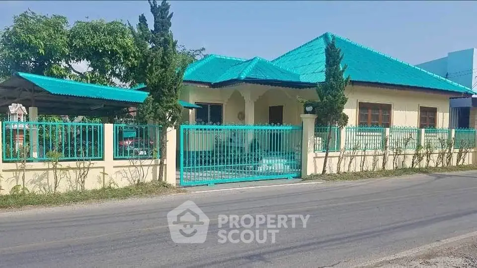 Charming single-story home with turquoise roof and gated entrance on a sunny day.