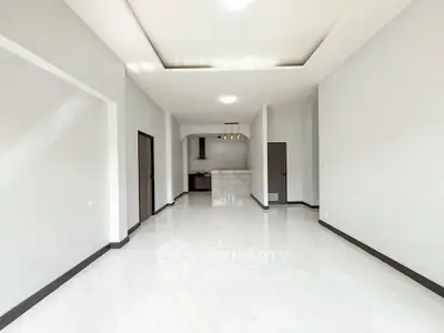 Spacious modern living room with sleek white flooring and open kitchen layout.