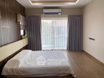 Spacious bedroom with modern design and large window offering natural light.