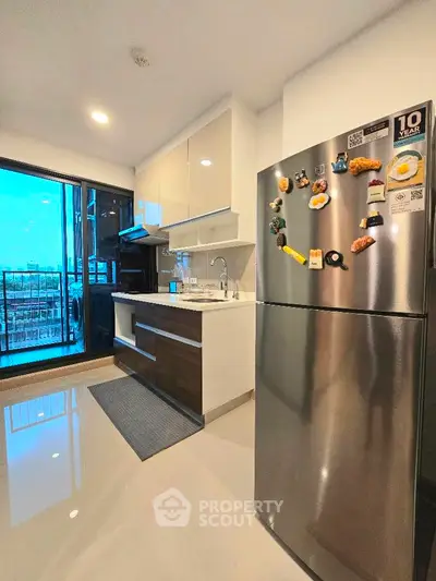 Modern kitchen with sleek cabinets and stainless steel fridge in a bright apartment.