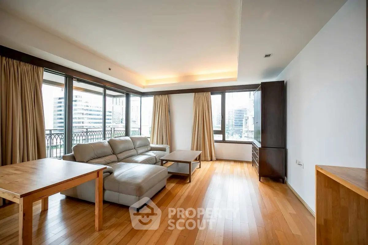 Spacious living room with hardwood floors and large windows offering city views.