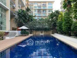 Luxurious apartment complex with serene pool and lush greenery