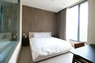 Modern bedroom with large windows and elegant wooden accents in a stylish apartment.