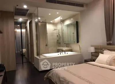 Luxurious bedroom with ensuite glass-walled bathroom featuring a modern bathtub.
