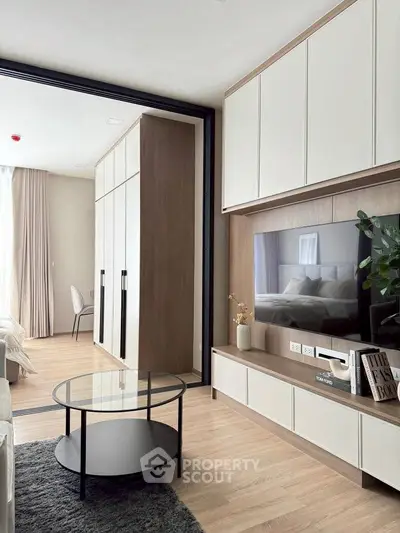 Modern living room with sleek TV unit and glass coffee table, showcasing elegant interior design.