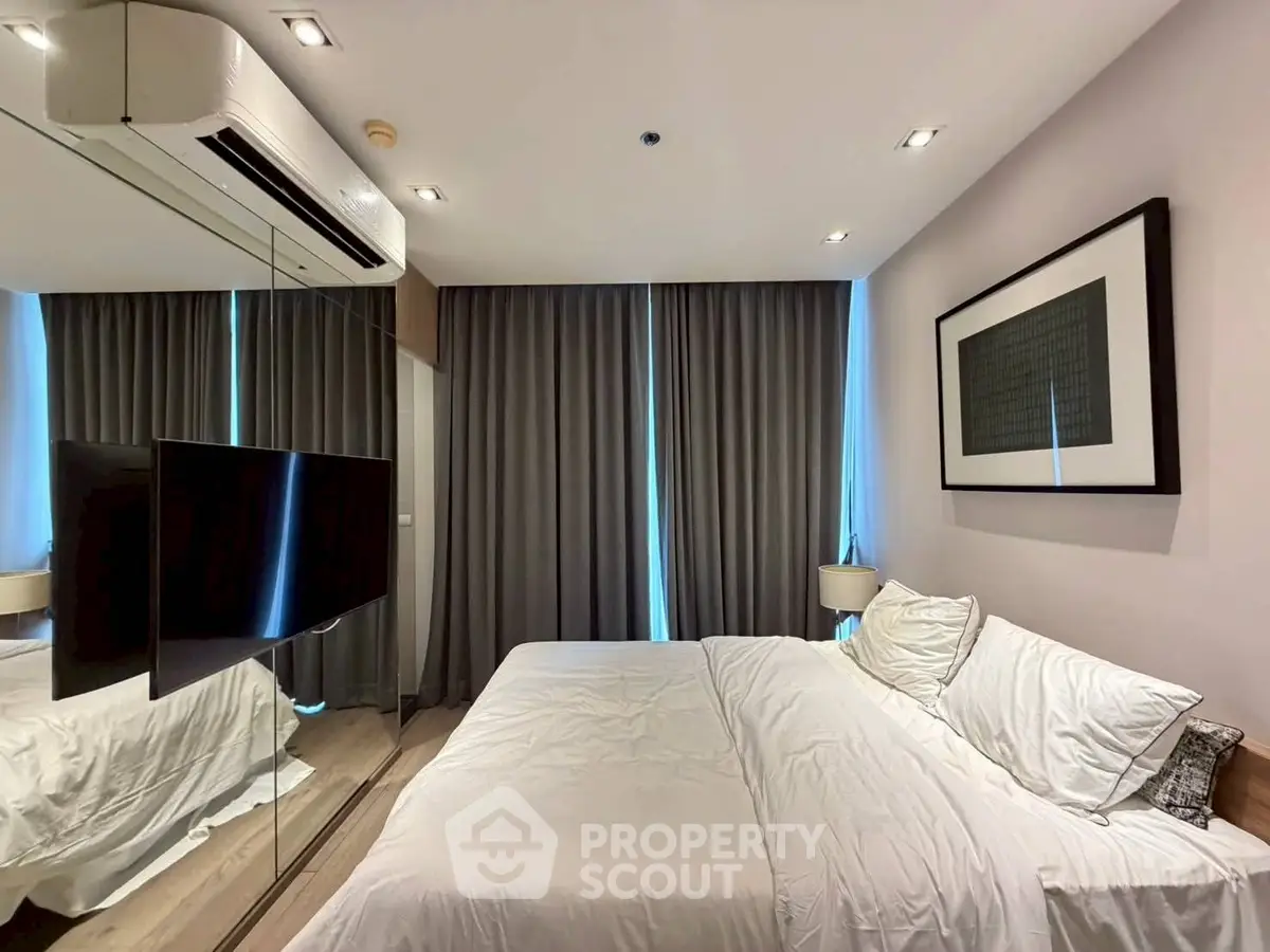 Modern bedroom with sleek design, mirrored wall, and cozy bedding in a stylish apartment.