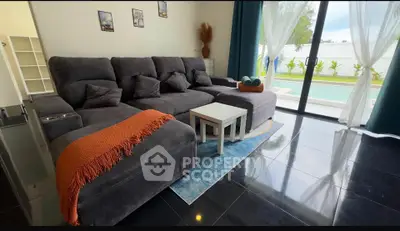 Luxurious living room with plush gray sectional sofa and pool view, perfect for relaxation.