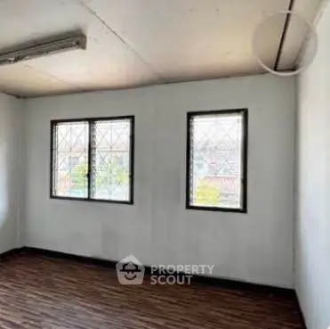 Spacious room with wooden flooring and large windows for natural light