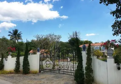 Charming gated entrance to a lush garden estate with blue sky backdrop.