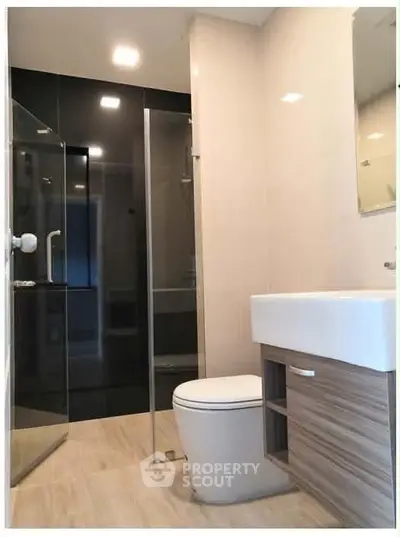 Modern bathroom with glass shower and sleek fixtures in contemporary apartment.