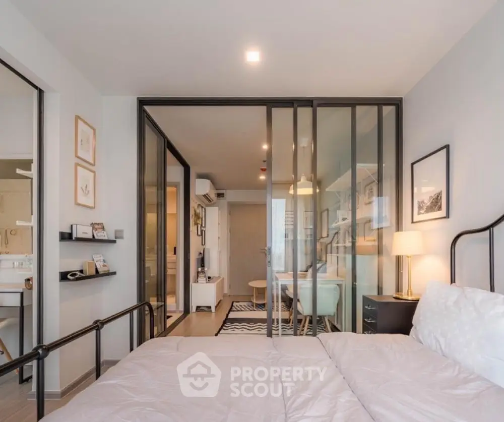 Modern bedroom with sliding glass doors leading to a cozy living area, featuring stylish decor and ample natural light.