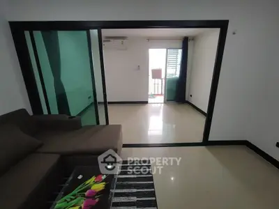 Modern living room with sliding glass doors leading to a balcony, featuring a sleek sofa and stylish decor.