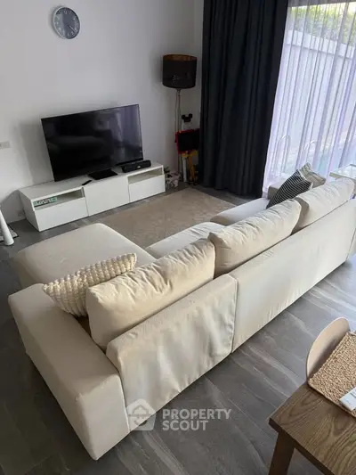 Modern living room with sleek furniture and large window, perfect for relaxation and entertainment.