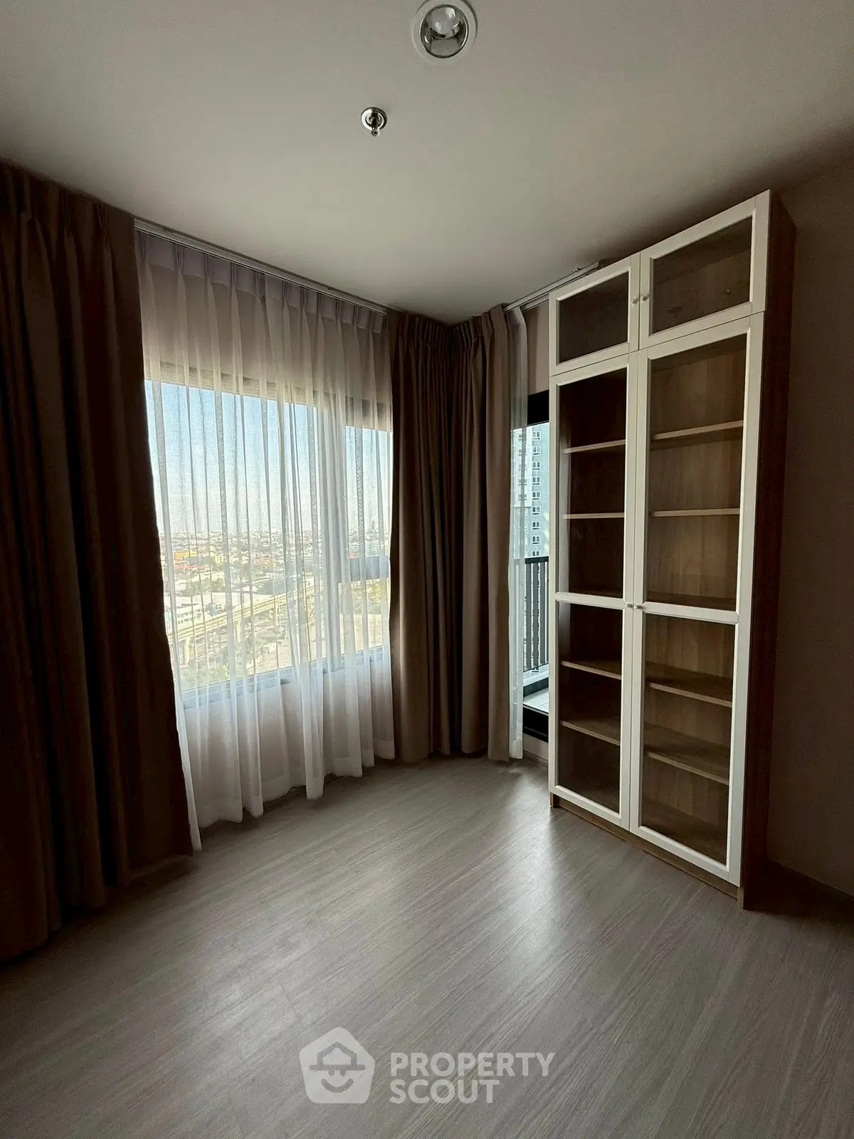 Spacious room with large window and built-in shelving, perfect for versatile use.