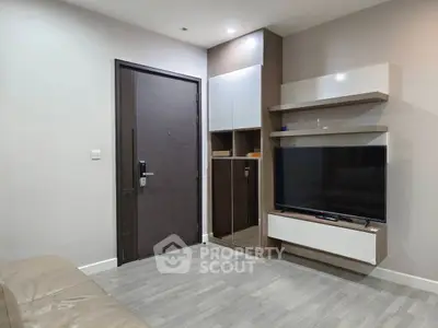 Modern living room with sleek furniture and large TV, showcasing minimalist design and functionality.
