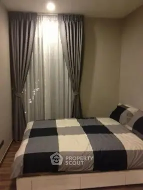 Cozy bedroom with stylish curtains and modern bedding in a contemporary apartment.